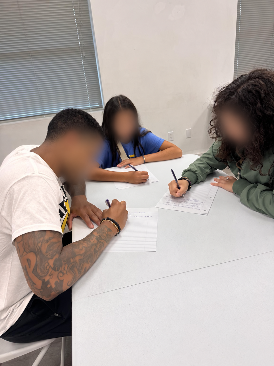 Participants completing guided journaling exercises at a community event; faces blurred for privacy